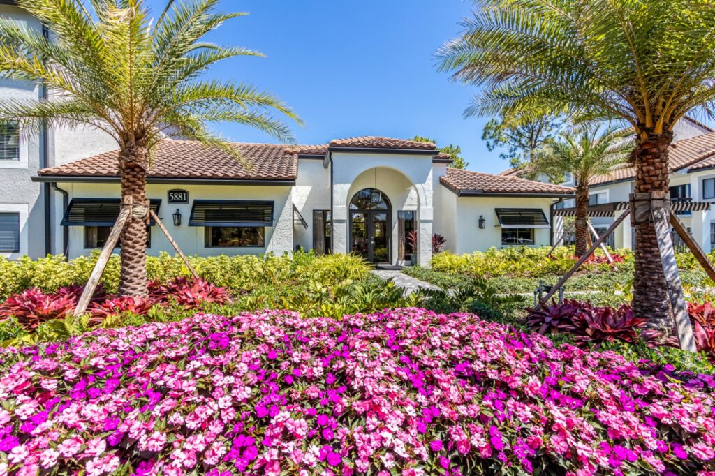 View of leasing office, 5881 with pink flowers in the front and palm trees