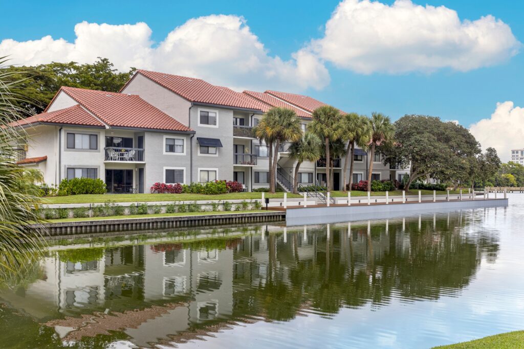 Lake with apartment complex in the back and palm trees.