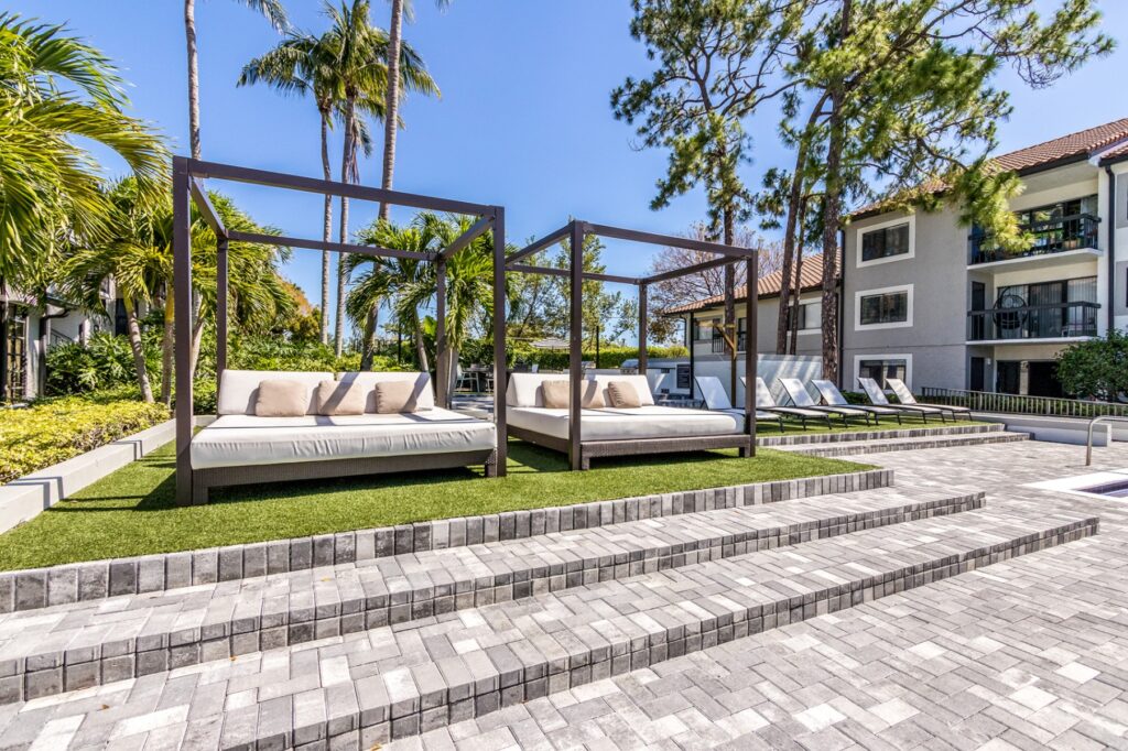 Steps leading out door cabanas and lounge chairs. Palm trees in the background.