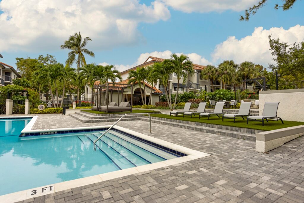 Pool steps with lounge chairs, cabanas, and palm trees in the back.